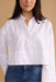 Person wearing a white button-up shirt and blue jeans against a beige background