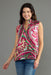 A woman modeling a sleeveless wrap-style top with a vibrant paisley and floral pattern in pink, green, and beige, paired with blue jeans against a solid gray studio background.