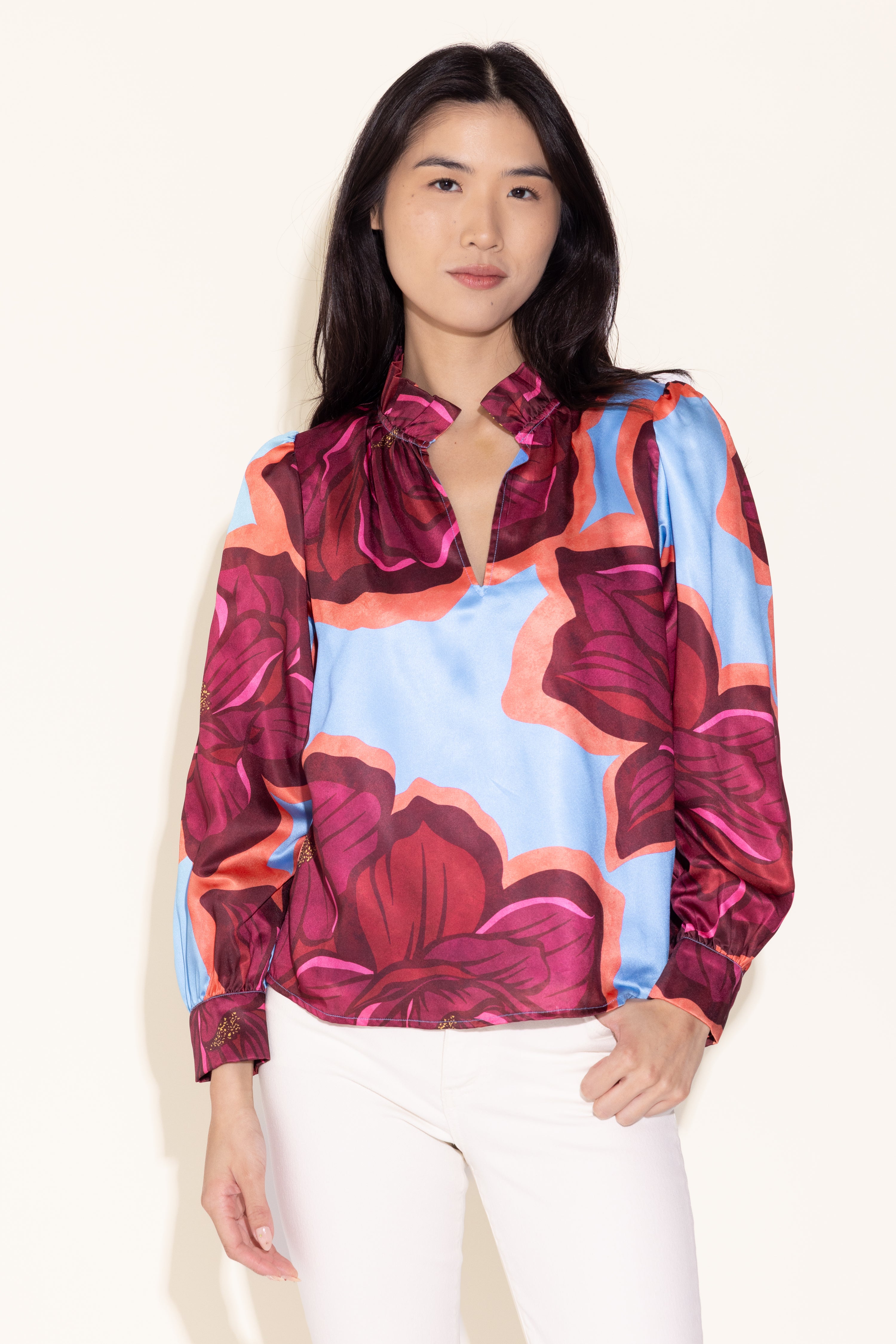 Woman wearing a colorful floral blouse with a plain background