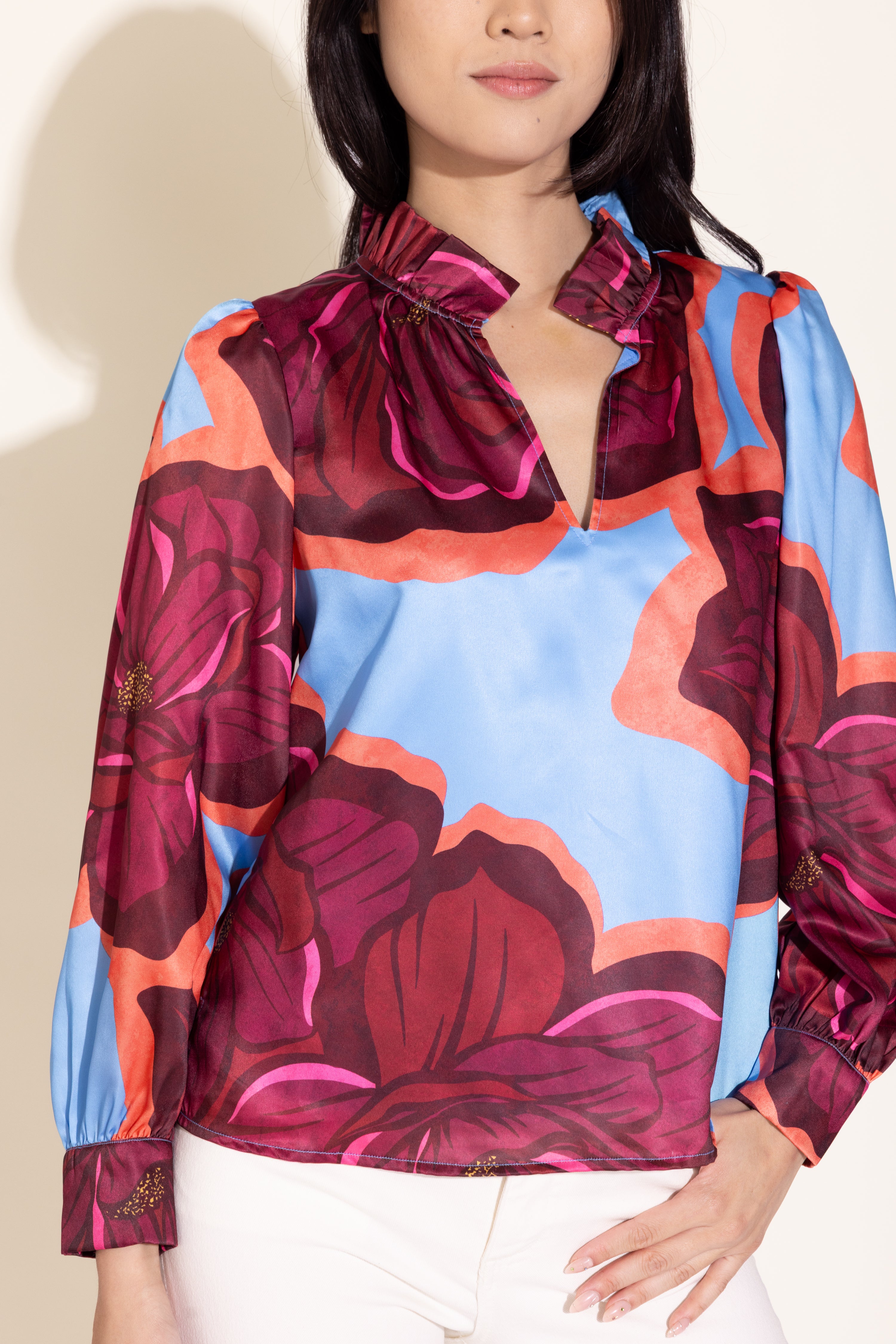 Woman wearing a colorful floral blouse with a plain background
