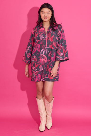 Woman wearing a patterned dress and pink boots against a pink background