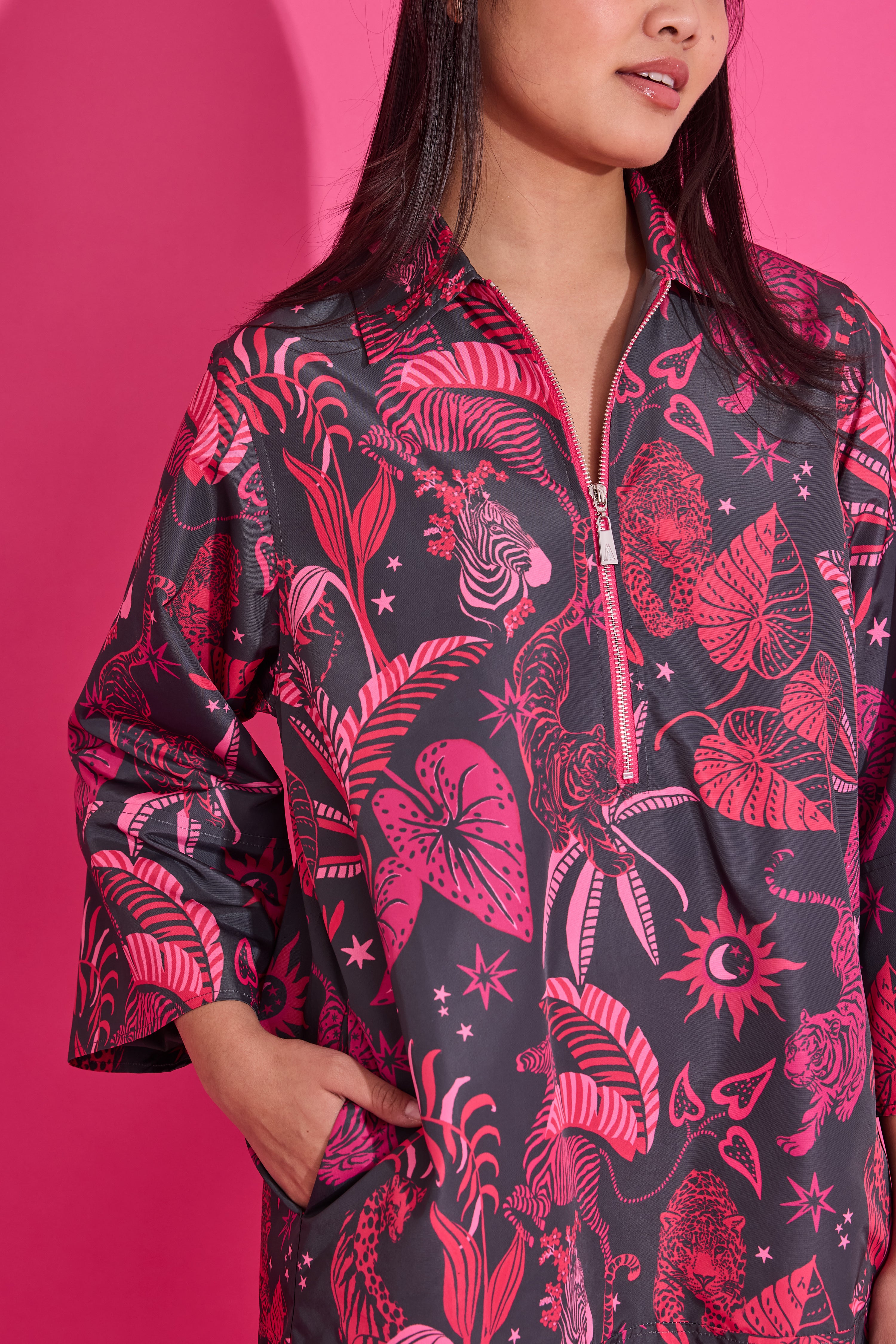 Person wearing a black and pink patterned shirt against a pink background