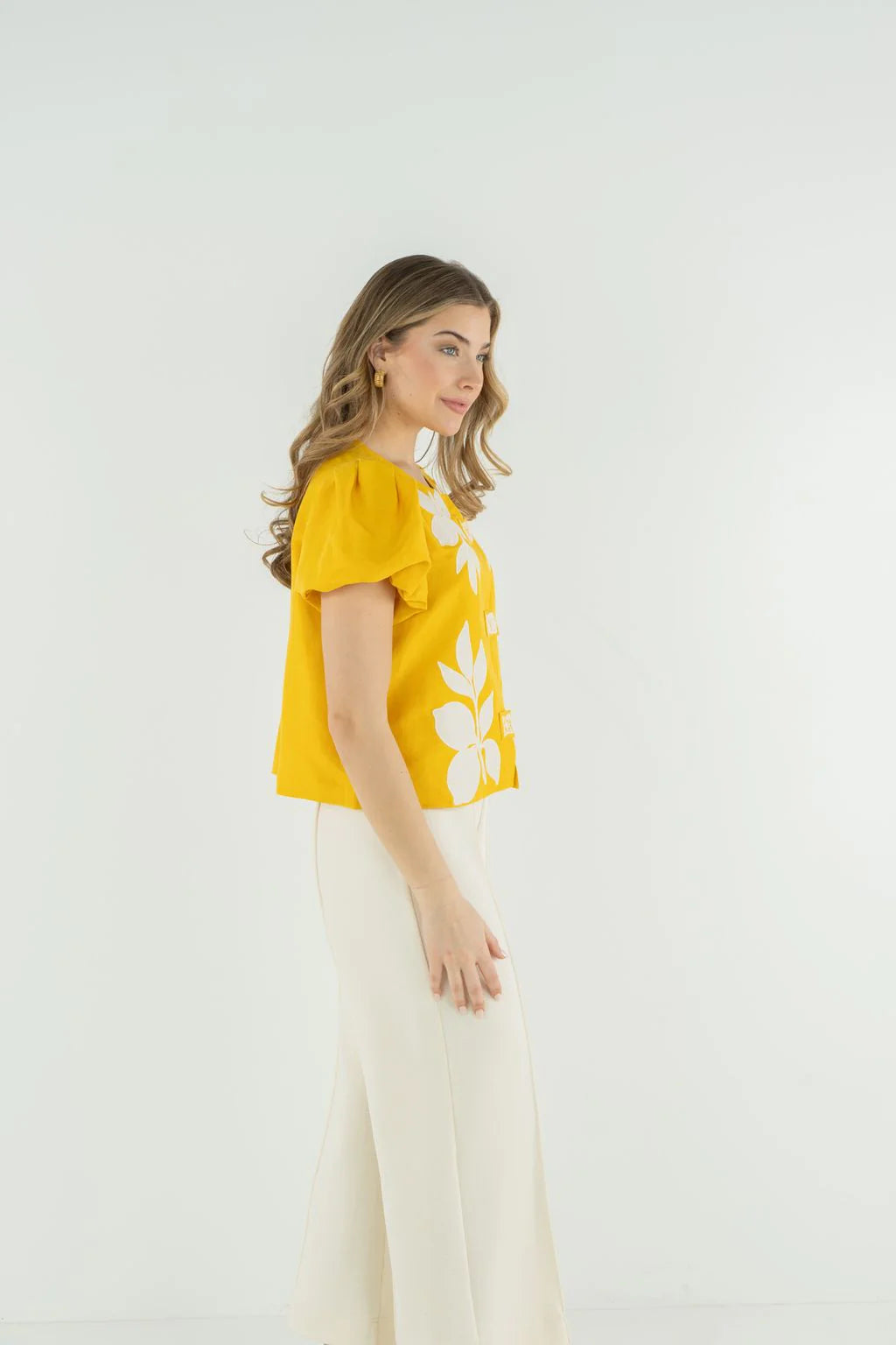 Woman wearing a yellow blouse with floral patterns on a white background