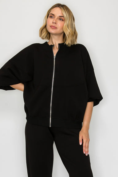 Woman wearing a black zip-up hoodie and pants on a white background